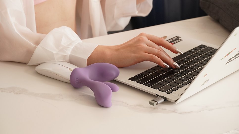 Woman types on laptop with vibrator on desk
