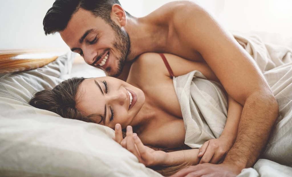 Couple cuddling in bed, relationship intimacy