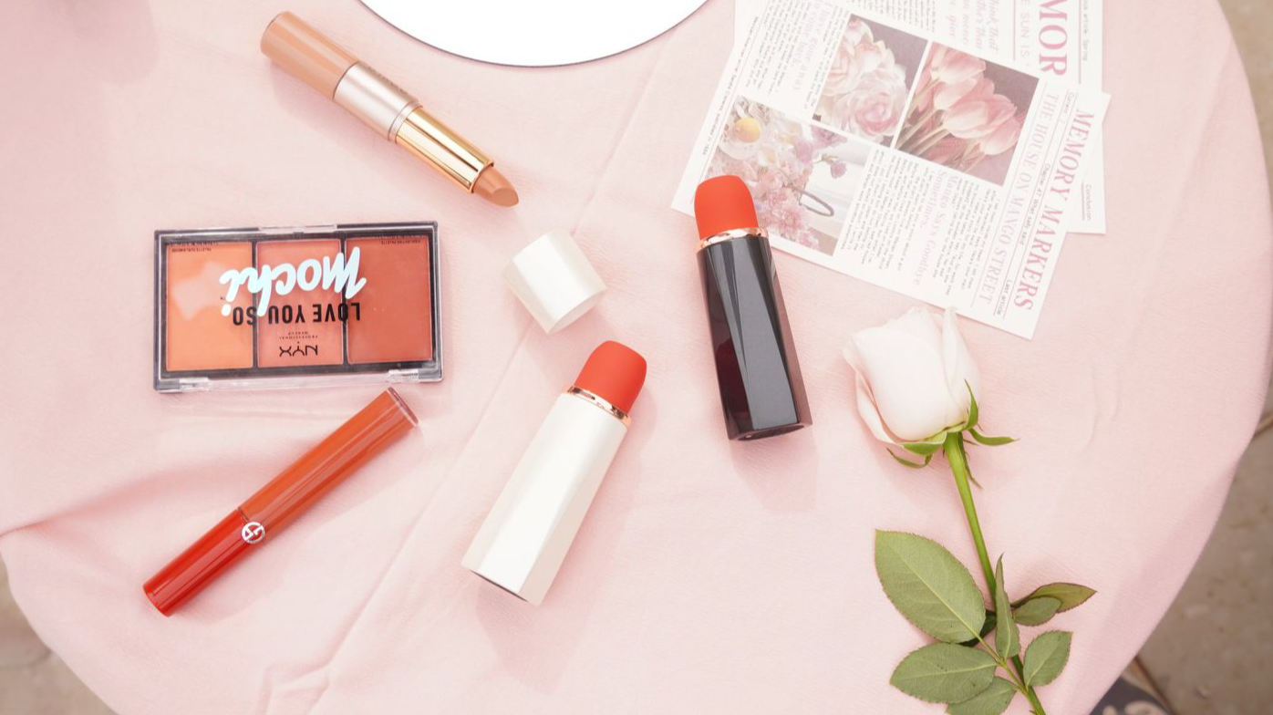 lipstick, blush, and rose on pink tablecloth
