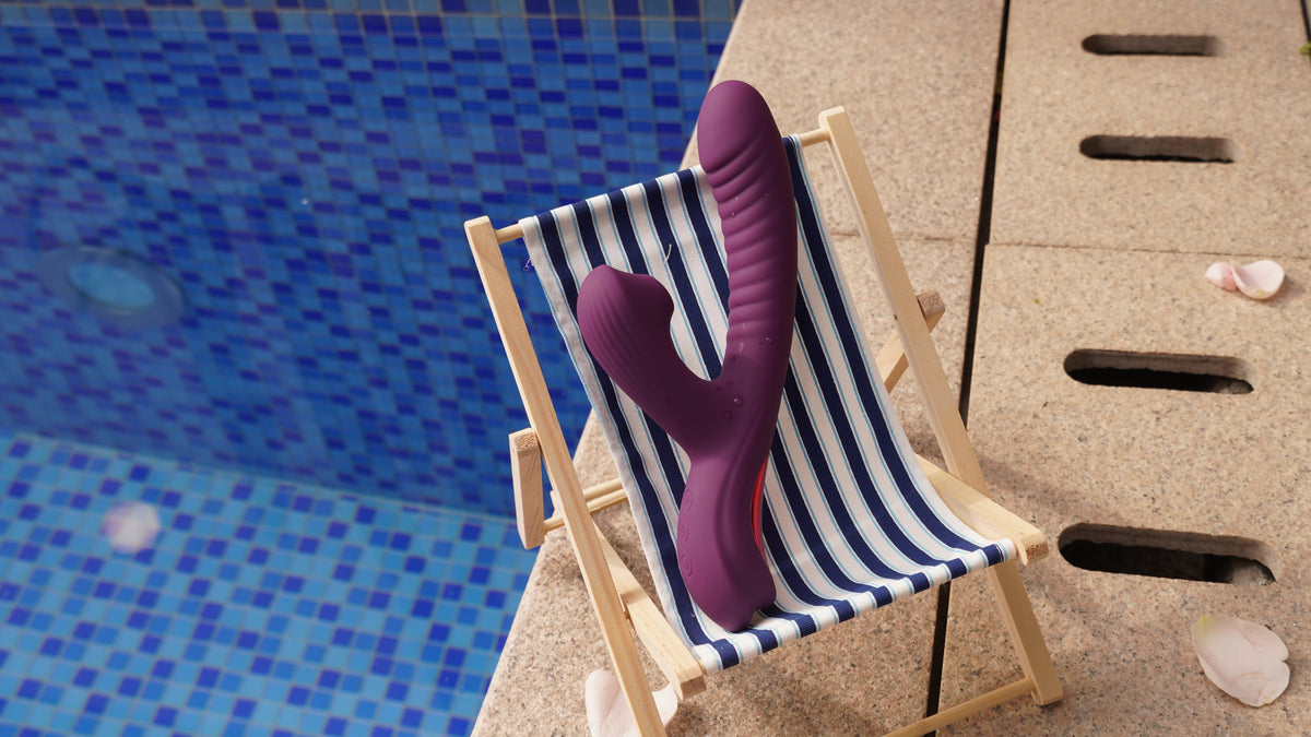 Purple 3-in-1 rabbit vibrator on striped deck chair beside pool