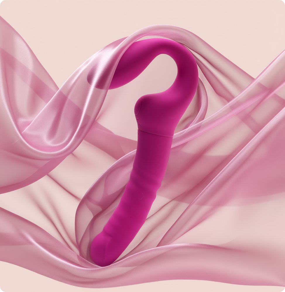 Pink silicone G-spot thrusting vibrator with curved tip on soft pink fabric