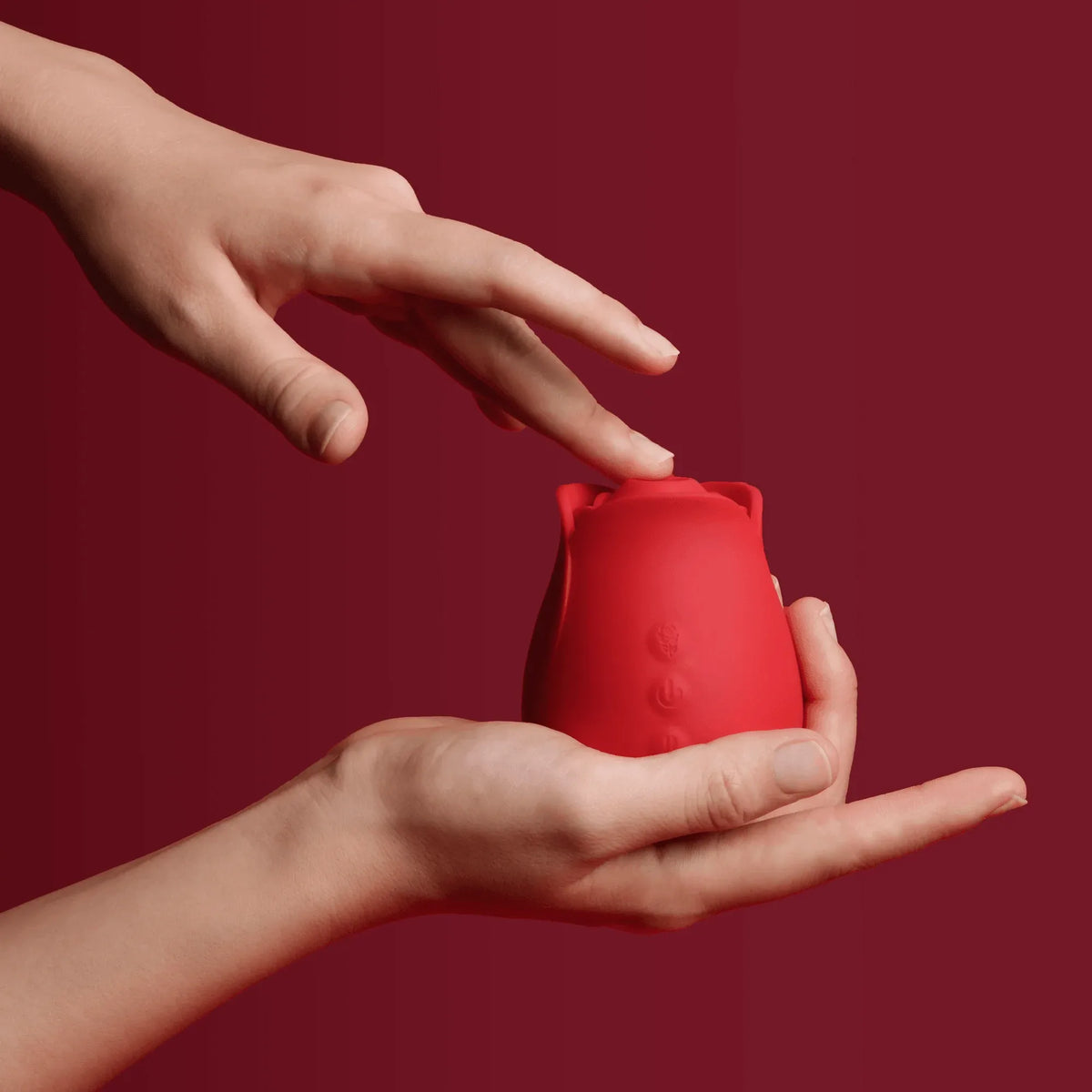 Red portable rose clit sucker held in hands with soft-touch controls