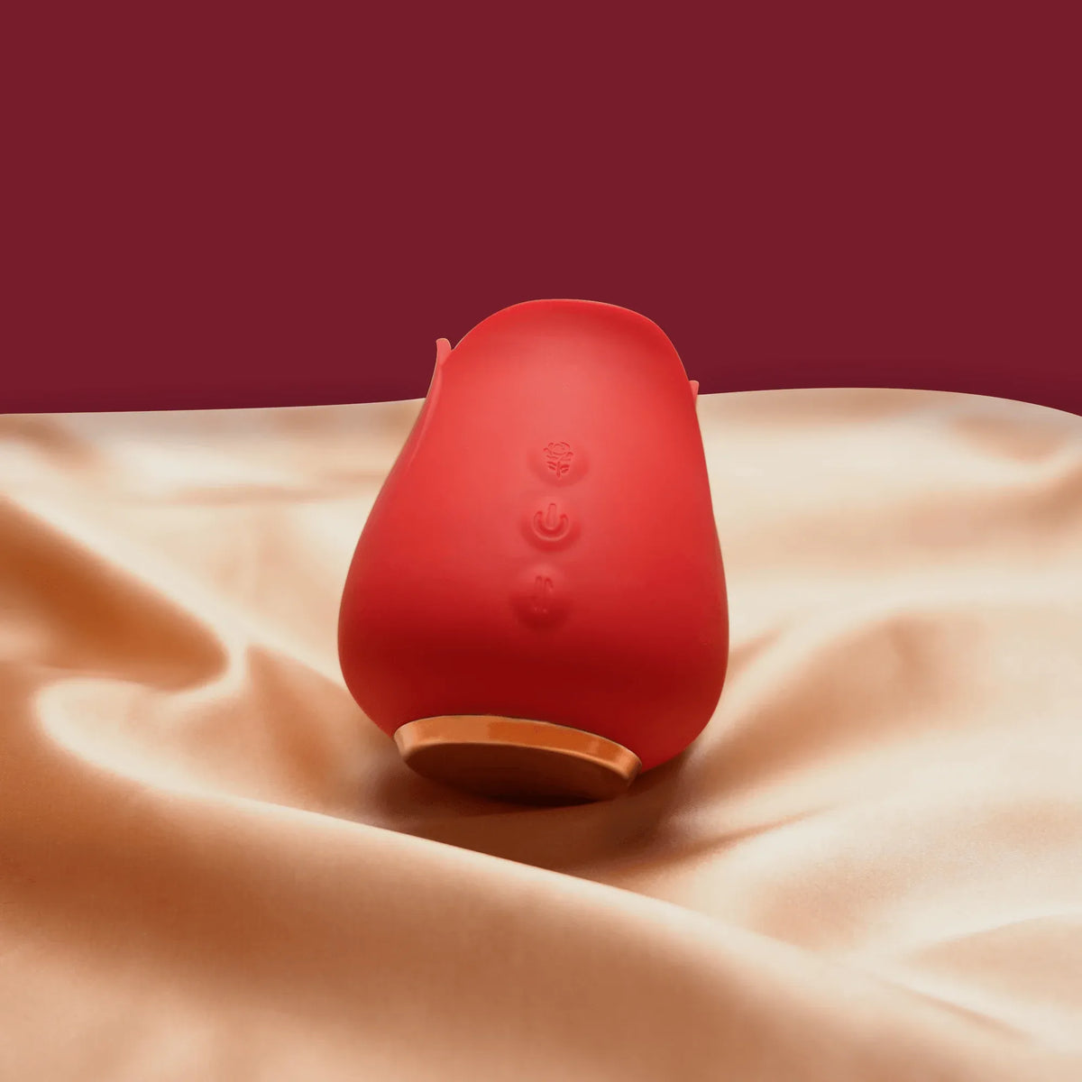 Red portable rose clit sucker with gold base on soft fabric