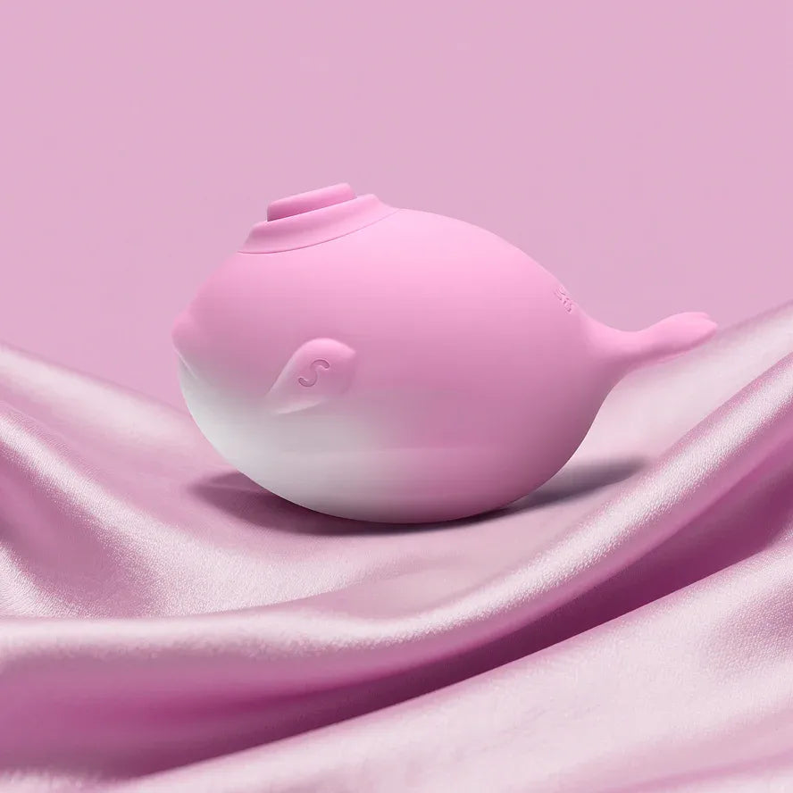 Pink whale-shaped silicone clitoral sucker on satin background