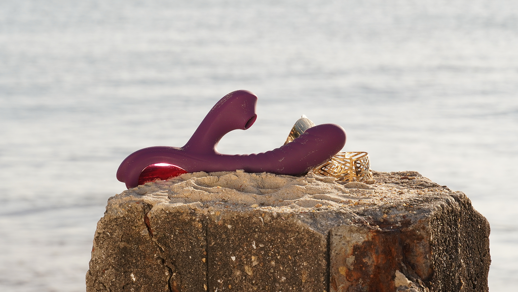Purple AI Drillme and AI Beta silicone pleasure devices on a stone block by water