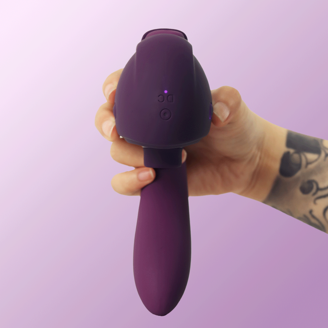 Hand holding purple OG 3 clitoral sucking vibrator with power button and curved shaft
